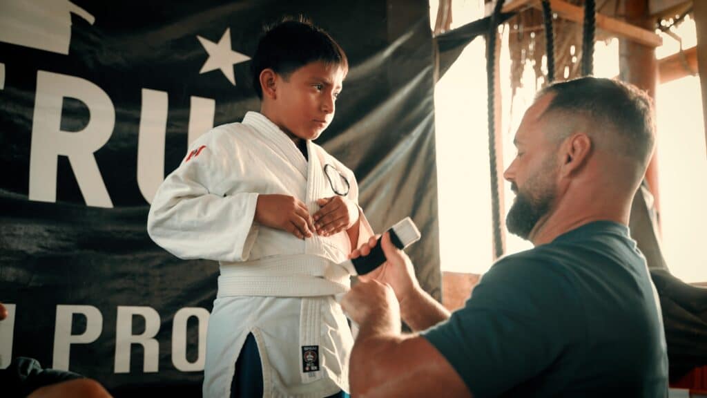 Fair Fight foundation member tying gi for kid.